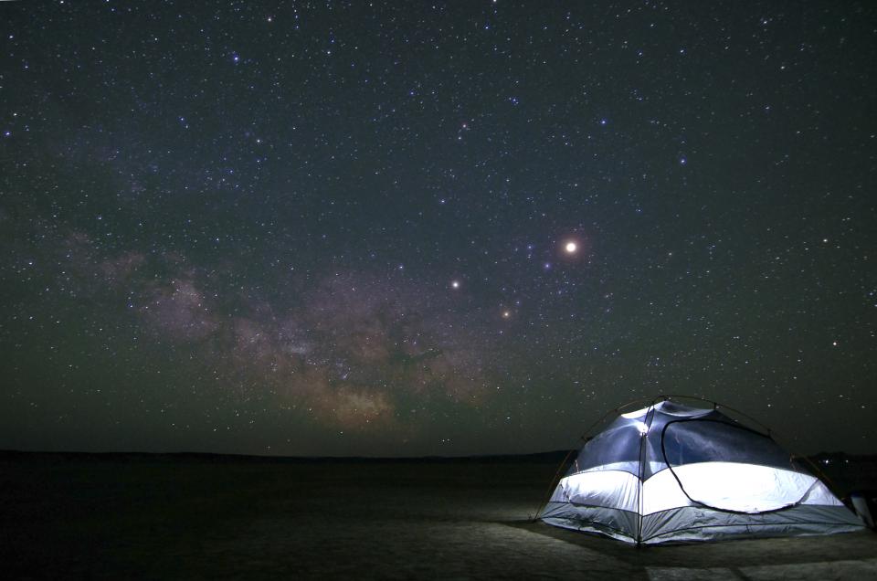 A lit tent under the Milky Way